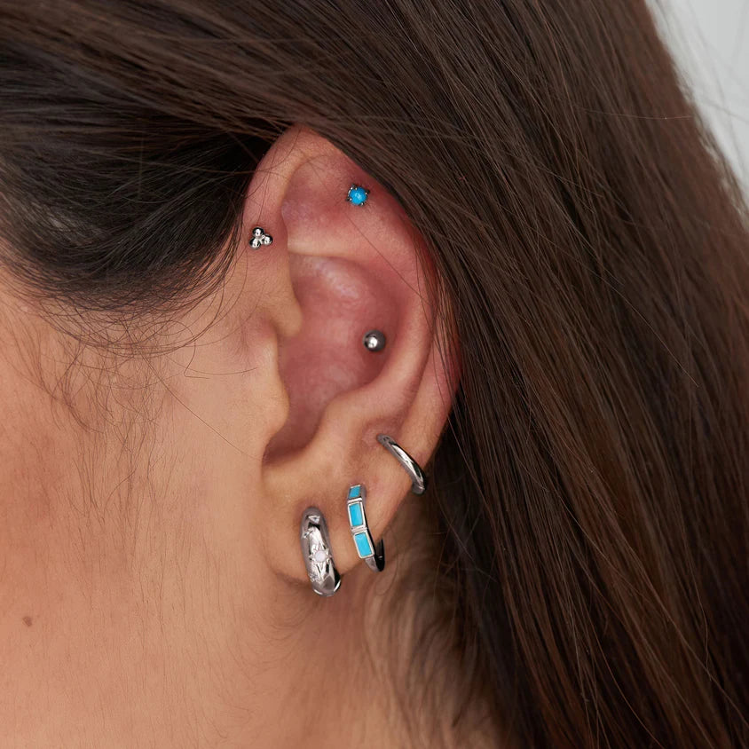 Close-up of an ear with multiple earrings and hair.